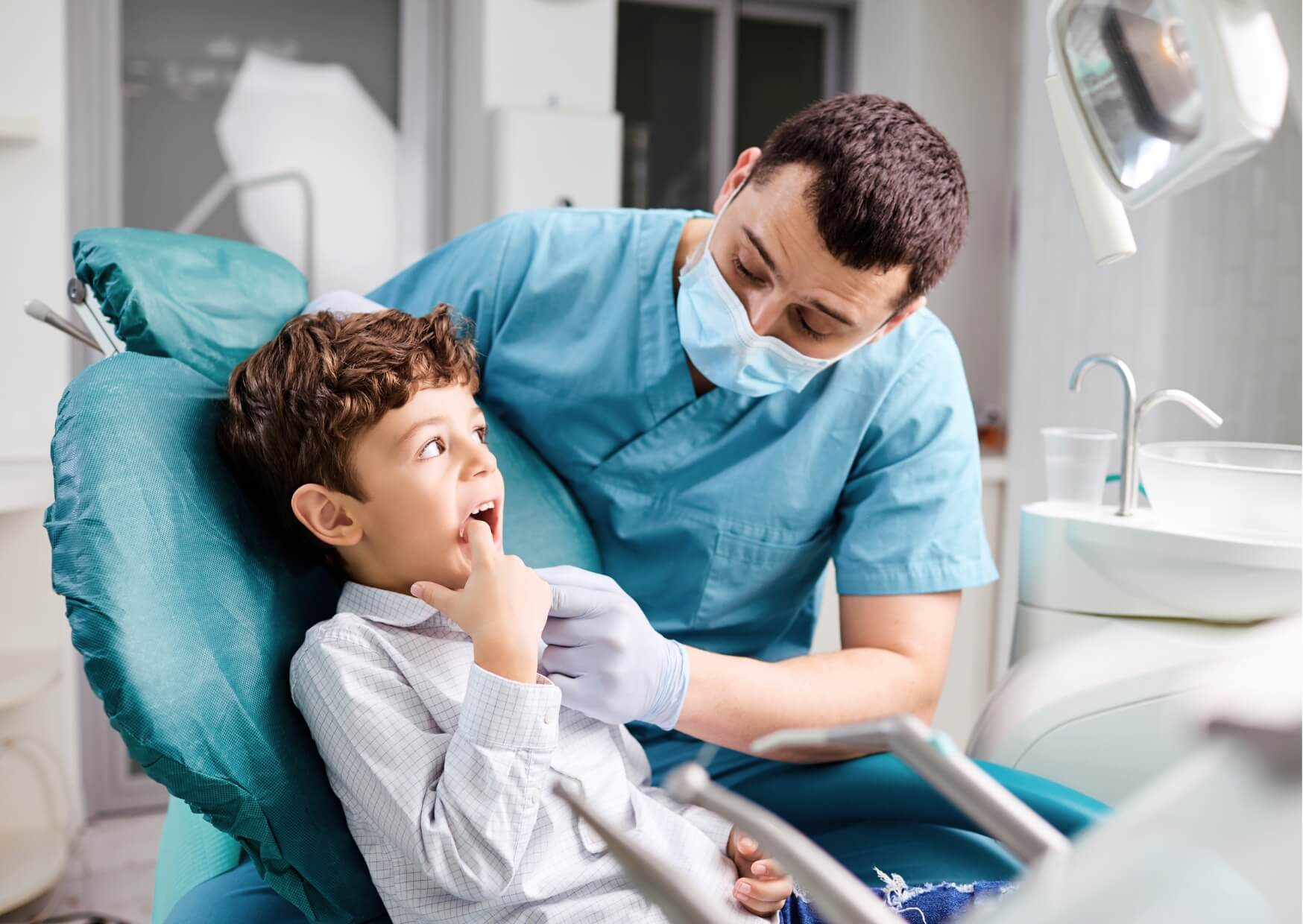 Pediatric dentist examining a young child during a dental visit to evaluate oral development and determine appropriate dental care timing.