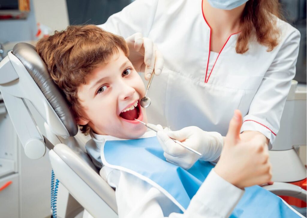 Child smiling with a thumbs-up during a pediatric dental visit before getting dental spacers to help maintain space for permanent teeth.