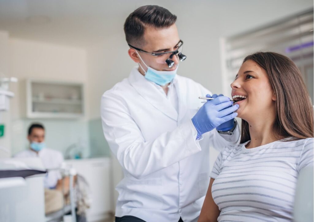 Dentist examining a young patient's mouth during an evaluation for erupting wisdom teeth and monitoring how a wisdom tooth is coming in.