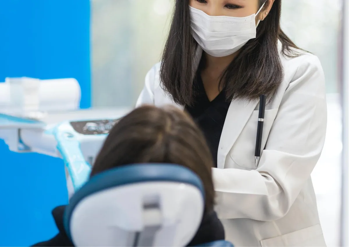 Dentist examining a patient to evaluate a canker sore and discuss how long canker sores typically last.