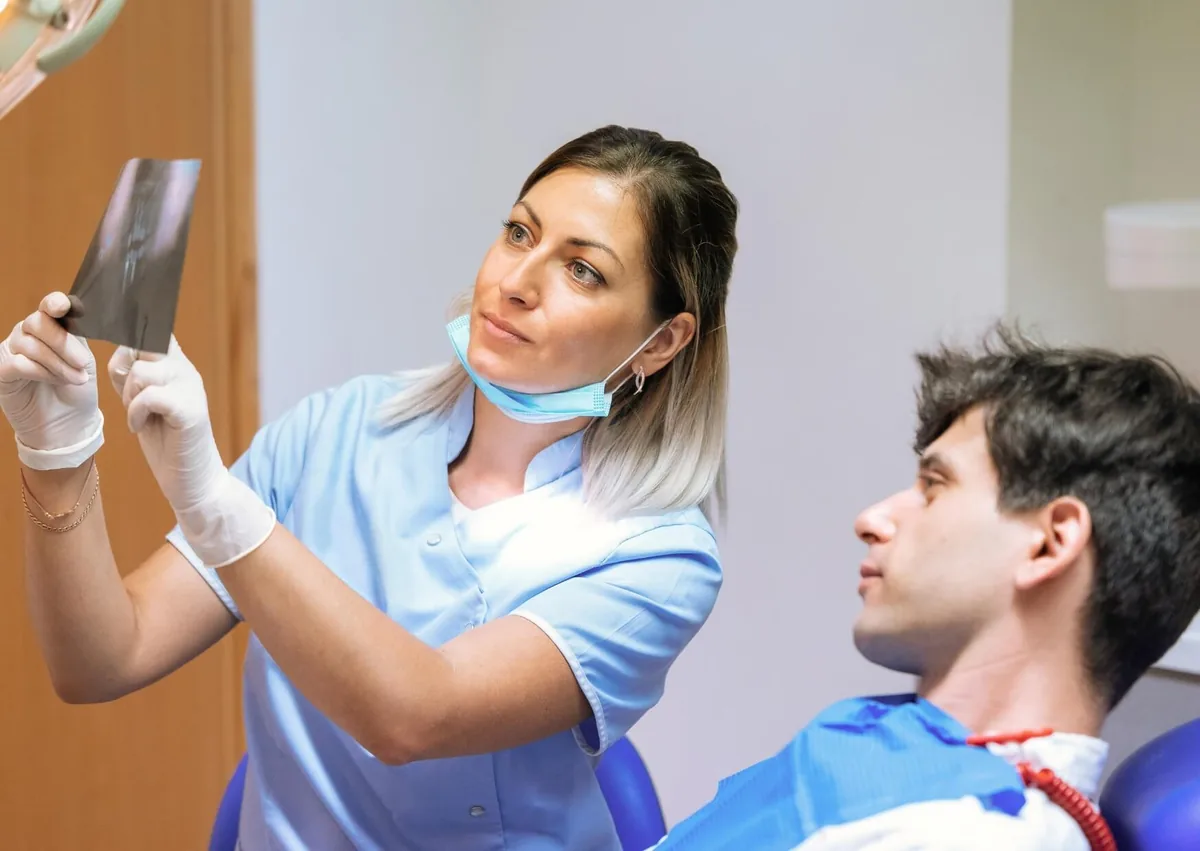 Dental professional reviewing an X-ray with a patient during a dental implant consultation.