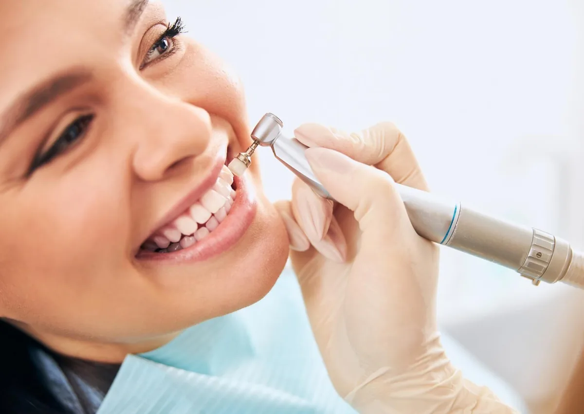 Dental professional removing plaque from a patient’s teeth during a professional cleaning.