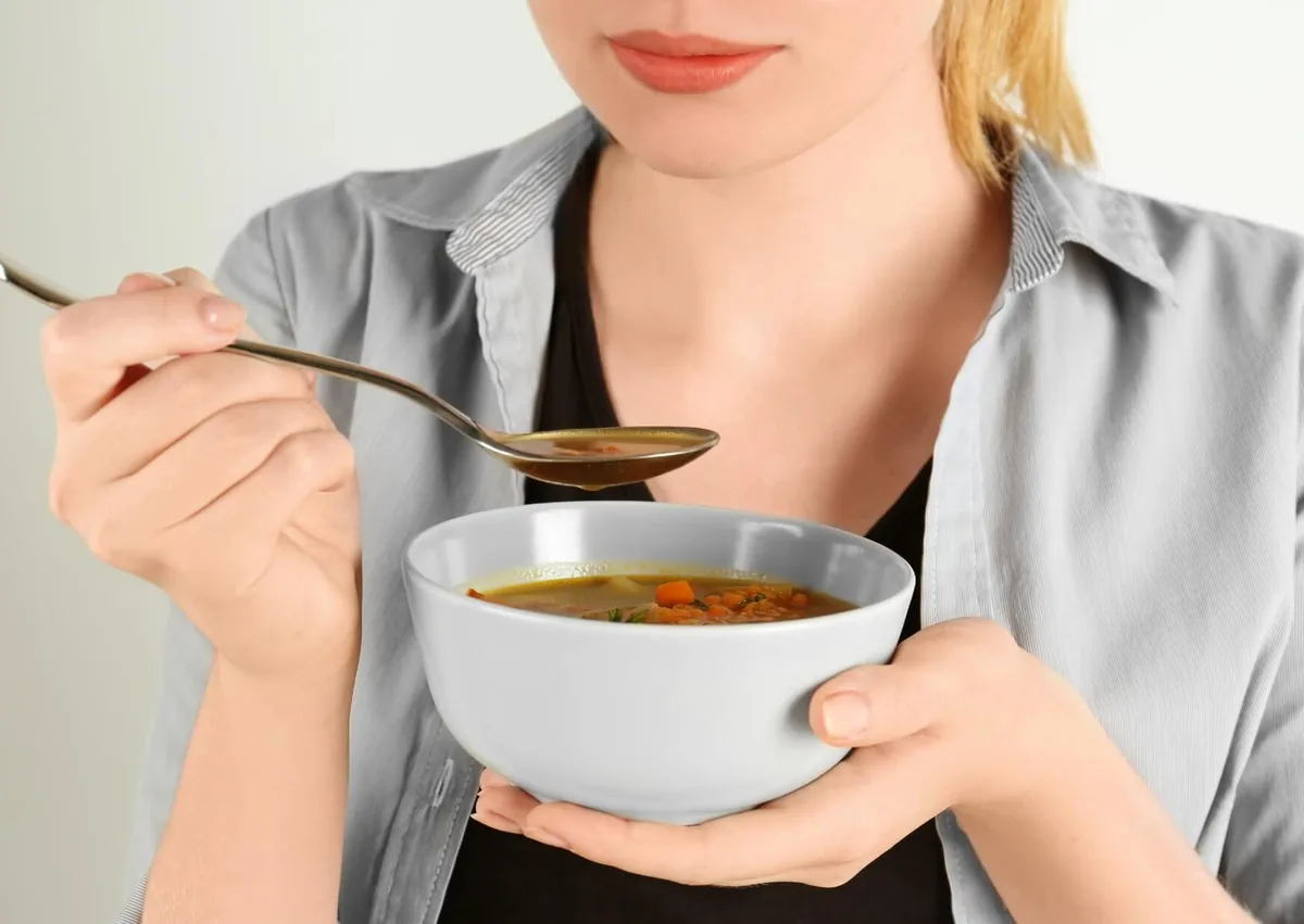 Woman eating soft soup as a meal option after wisdom teeth removal.